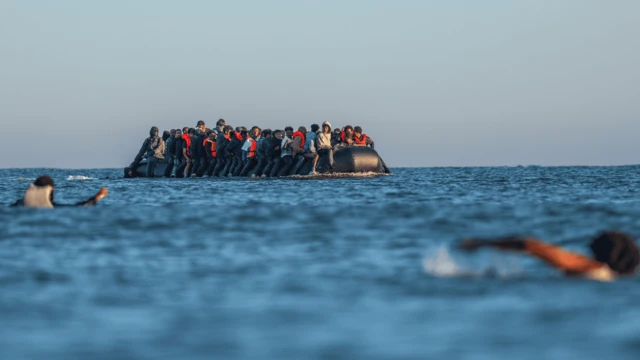 Gente nadando para intentar subir a un bote para migrantes hacia el Canal de la Mancha.