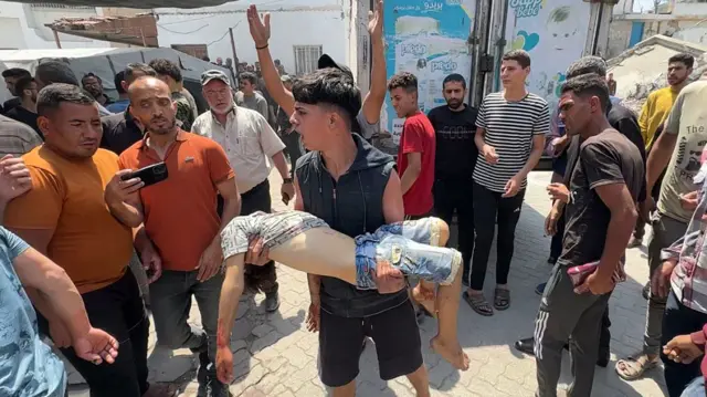 Палестинец несет раненого ребенка,