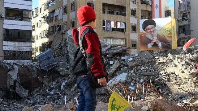 အဆောက်အဦးပျက်ကြားက ဟစ်ဇ်ဘိုလာ ခေါင်းဆောင်ဟောင်း ဟာဆန်နာဆာရာလာပုံကို ရပ်ကြည့်နေတဲ့ လူငယ်တစ်ဦး 