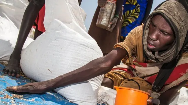 чоловік збирає зерно з підлоги