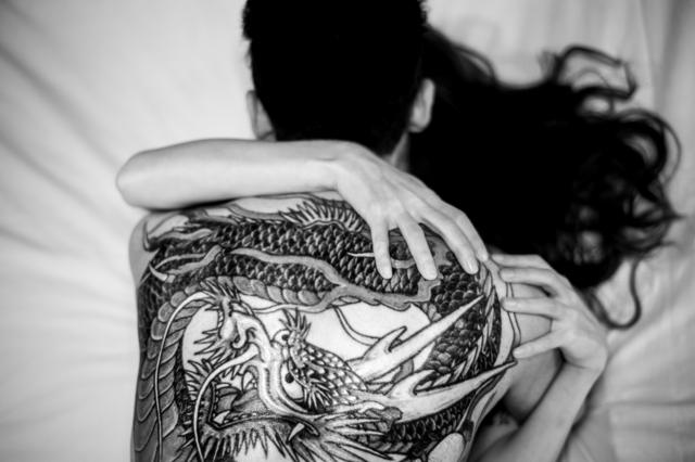 Casal abraçado com tatuagem à vista nas costas do homem