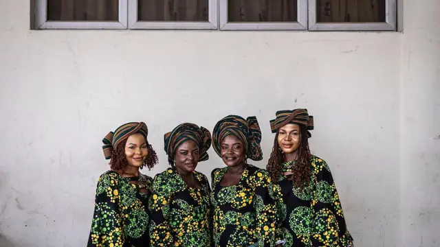 Twin sisters Taiwo and Kehinde Oketikun pose for a photograph with twin sisters Taiwo and Kehinde Adisa. All four wear matching multi-coloured outfits.