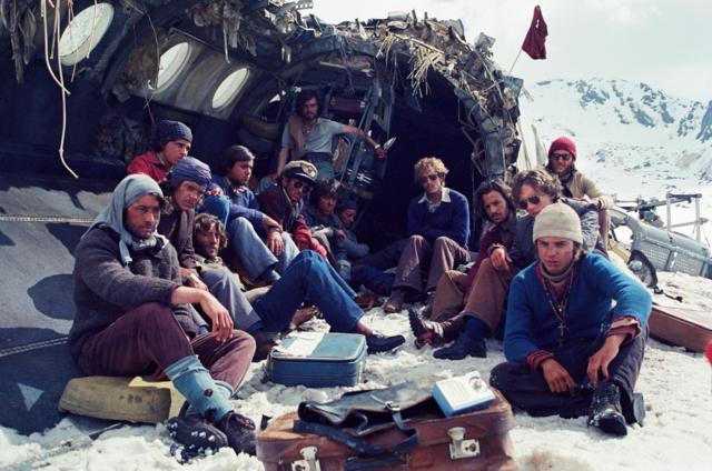 Los actores que interpretan a los 16 sobrevivientes en una escena de "La sociedad de la nieve" sentados afuera del fuselaje.