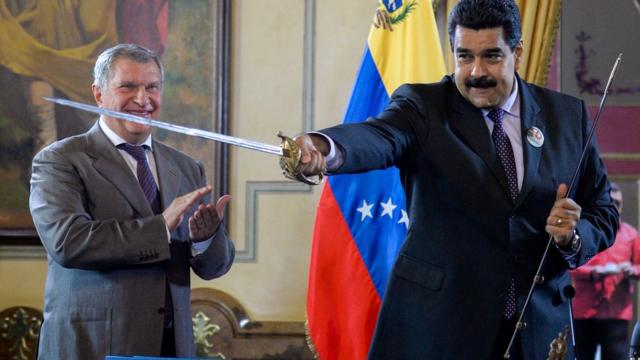 Nicolás Maduro, com uma espada na mão e ao lado do russo Igor Sechin que aplaude a cena
