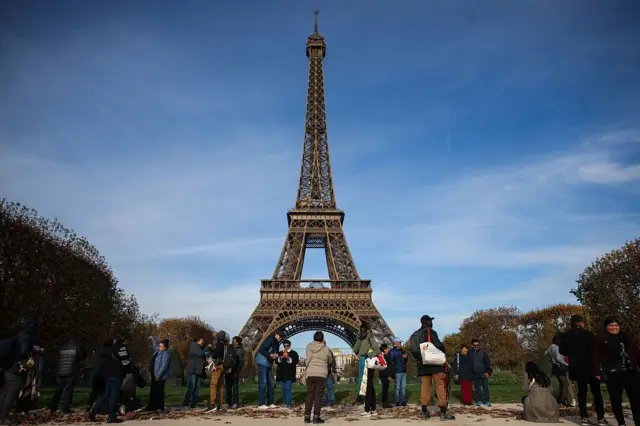 Des touristes se prennent en photos aux abords de la Tour Eiffel, un des monuments les plus visités au monde.