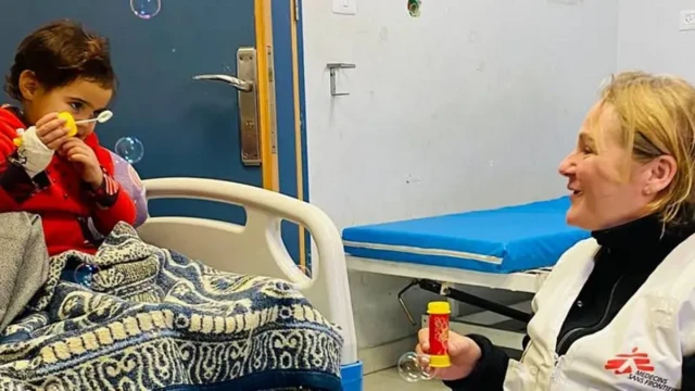 یک زن روی صندلی نشسته و یک اسباب‌بازی برای درست کردن حباب صابون در دست گرفته، روبروی او دختربچه‌ای روی تخت در حال درست کردن حباب صابون است