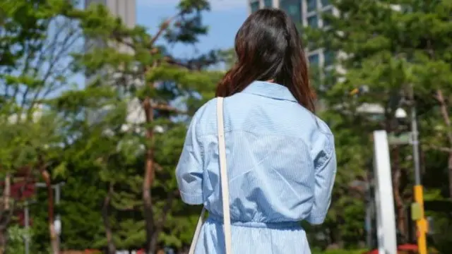 Kang Gyuri de espaldas con un vestido a rayas. 