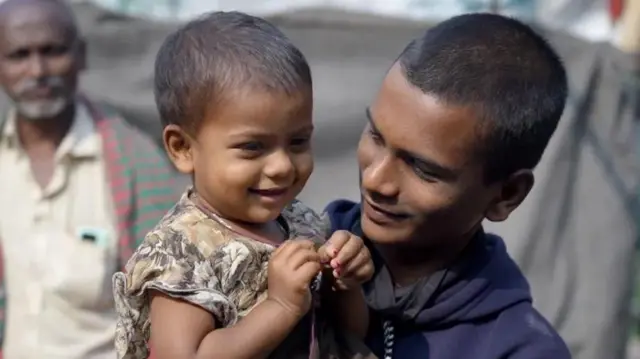 Rithick, kaka mdogo wa Dipu, anamlea mtoto wa miezi 18 Gitika nje ya nyumba yao huko Mymensingh