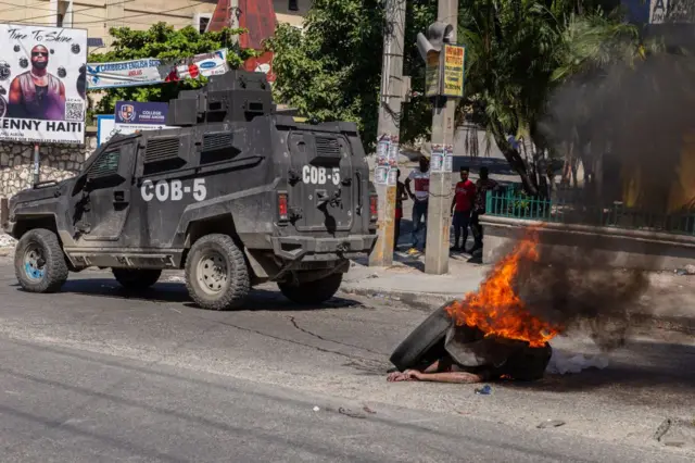 Una tanqueta de la policía frente a un cuerpo en llamas de un pandillero en Puerto Príncipe, Haití, el 19 de noviembre de 2024.