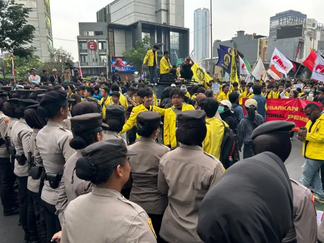 Polisi membentuk barikade di depan mahasiswa.