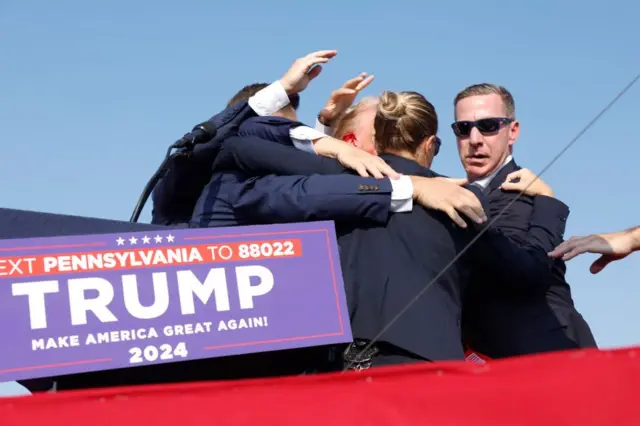  El candidato republicano a la presidencia de EE.UU., el expresidente Donald Trump, es sacado a toda prisa del escenario durante un mitin el 13 de julio de 2024 en Butler, Pensilvania.