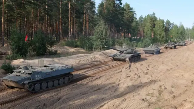 Танк колоннаси ўрмон четидаги қум йўл бўйлаб ҳаракатланмоқда