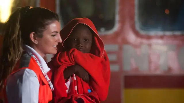 ভূমধ্যসাগর থেকে উদ্ধার হওয়া এক আফ্রিকান শিশুকে নিয়ে যাচ্ছে স্পেনের একজন স্বাস্থ্যসেবক।