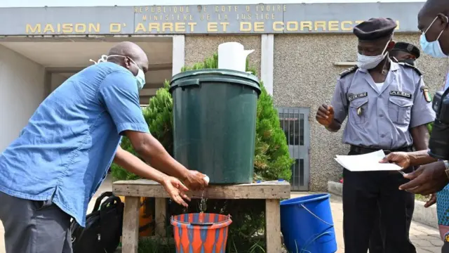 Un homme se lave les mains à l'entrée de la prison centrale d'Abidjan