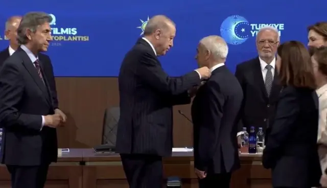 Erdoğan rozetini Özcan'a takıyor. 