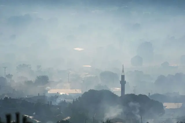 Ödemiş ilçesindeki bir mahallenin 4 Temmuz'daki görüntüsü, bir cami minaresi görünüyor ve büyük bir duman tabakası arasında evler görünüyor
