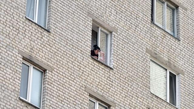 乌克兰女子从公寓楼窗口朝外看