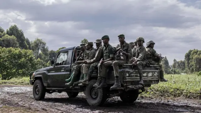 Des combattants armés du M23 sont assis à l'arrière d'un pick-up.