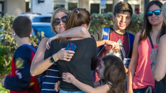 Familiares e crianças se abraçam nos arredores da escola pública Marjory Stoneman Douglas