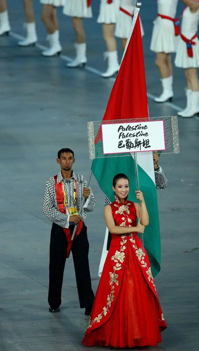 Nader el Masri avec le drapeau palestinien suivant une femme tenant une pancarte de la Palestine.