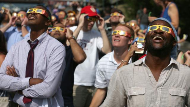 Com óculos, pessoas observam eclipse