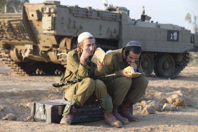 جنود إسرائيليون يؤدون صلاة الفجر في منطقة انتشار للجيش الإسرائيلي بالقرب من الحدود بين إسرائيل وقطاع غزة