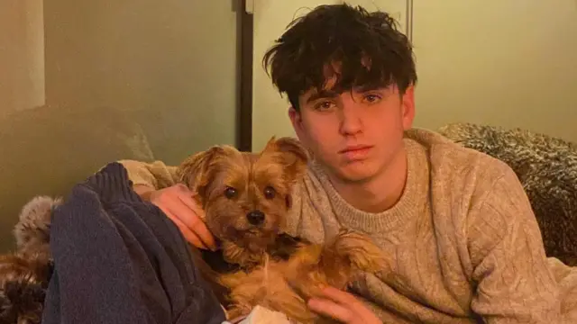 Arthur Brodard siedzi na sofie i głaszcze psa