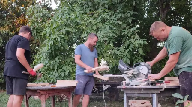 Tri muškarca rade za mašinama za preradu drveta