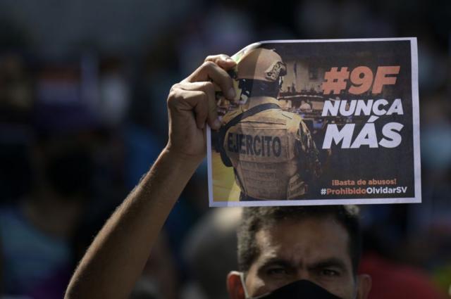 Un estudiante de la Universidad de El Salvador sostiene un cartel que dice "#9F nunca más" durante una manifestación contra el presidente salvadoreño Nayib Bukele, un año después de la incursión militar en la Asamblea Legislativa, en San Salvador, el 9 de febrero de 2021.