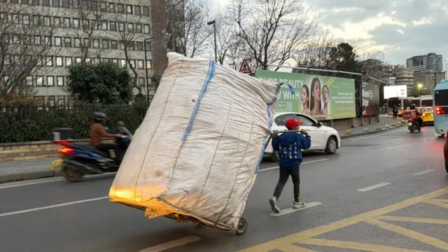 Söğütlüçeşme'deki Kadıköy Belediyesi binası önündeki yolda çekçek ile çalışan bir çocuk işçi. Çuvalın neredeyse yarı boyundaki çocuğun üzerinde mavi bir sweatshirt, kafasında ise Örümcek Adam şapkası var.