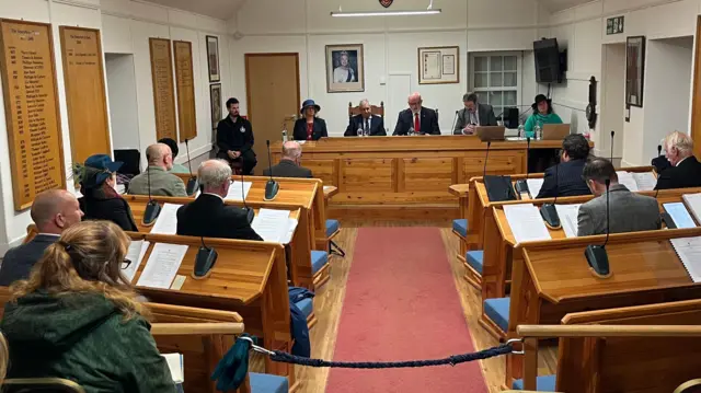 Pleitos principales: Un entorno de sala de audiencias con varias personas sentadas detrás de escritorios.