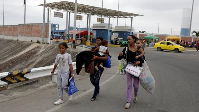 Venezuelans walk together with their children after entering Peru