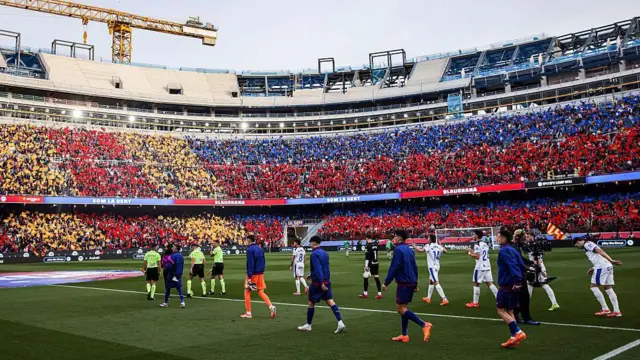 ورود بازیکنان بارسلونا و آلاوس در زمین نیوکمپ در یکی از مسابقات فوتبال.