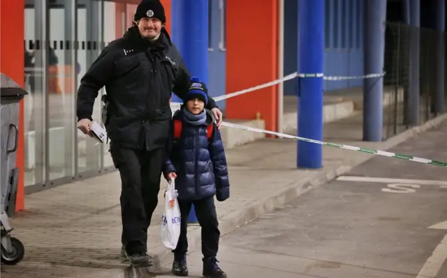 Boy holding his bags is seen with a Slovak policeman