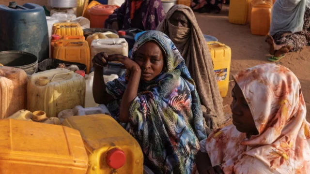 سيدات سودانيات يجلسن في الصحراء مع أواني انتظاراً لقدوم المساعدات والمياه
