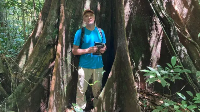 Dom pose pour une photo devant un arbre gigantesque.