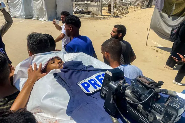 हमले में घायल एक पत्रकार को अस्पताल ले जाते लोग 