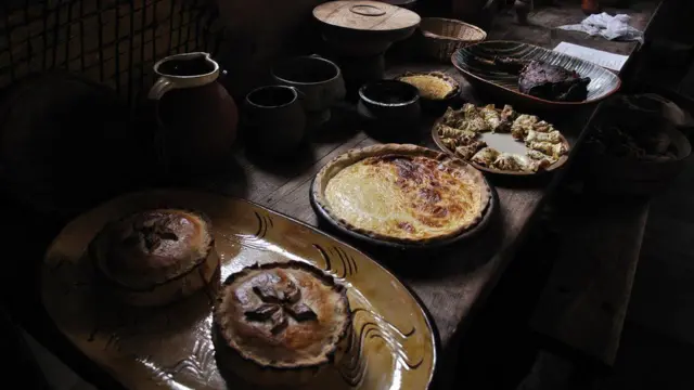 Темный стол с пирогами с мясом и глиняными горшками