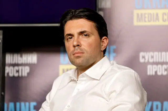 Кудрицький у білій сорочці дивиться в камеру