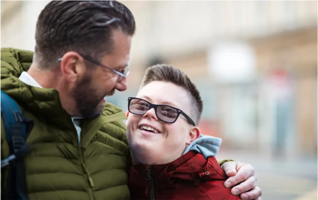 Un adulte tenant un adolescent serré contre lui