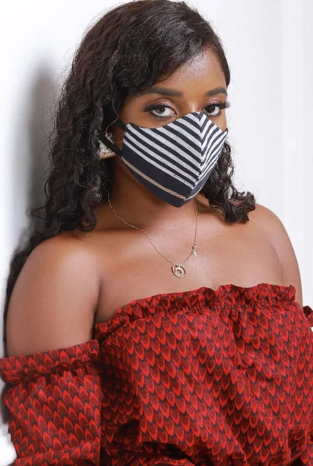 La mannequin et influenceuse Dibaussete porte un masque fait en tissu tissé Aso Oke (chez les yoruba) et Kanvo (en fon), haut chiganvi de la marque Eldior Sodeck