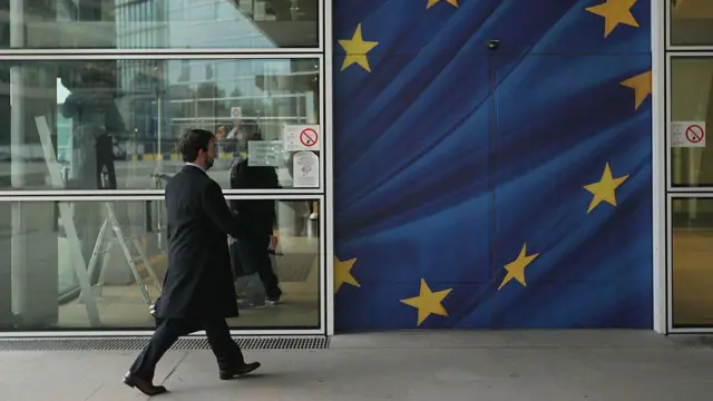 
Um homem atravessa uma porta com a bandeira da União Europeia pintada nela.