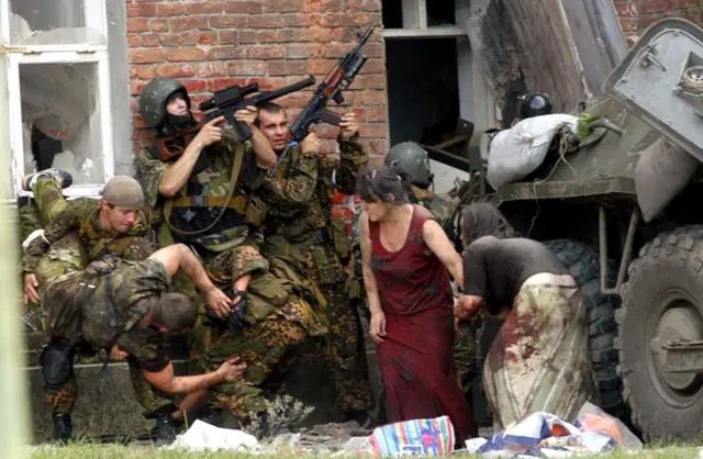 Militares rusos junto a civiles afuera de la escuela durante el asedio.