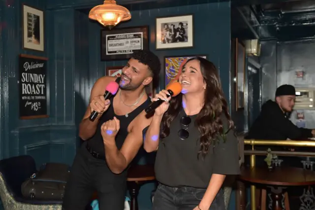 Duas pessoas cantando no karaokê