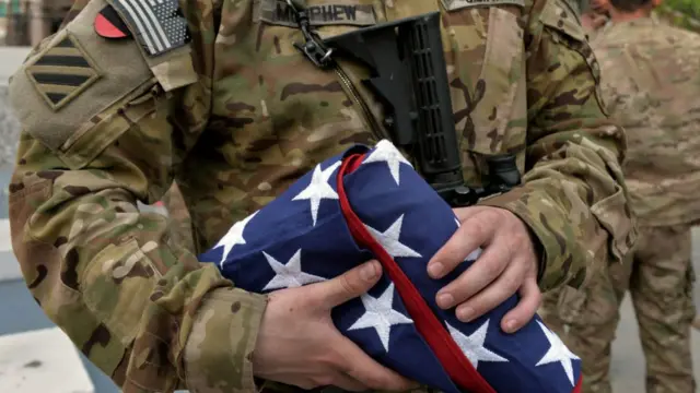 যুক্তরাষ্ট্রের পতাকা হাতে একজন মার্কিন সেনা।