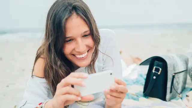 Mujer sonriendo al mirar su teléfono