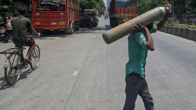একটি অক্সিজেন সিলিন্ডার জোগাড় করে নিয়ে যাচ্ছেন মুম্বাইয়ের একটি হাসপাতালের কর্মী