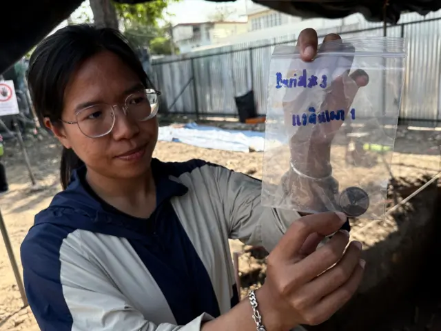 นภัสสร แย้มคงเมือง นักโบราณคดี แสดงแวดินเผาที่พวกเขาพบในแหล่งขุดค้น