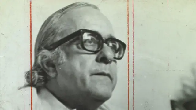 Foto em preto e branco mostra Vinicius de Moraes de perfil, de óculos, olhando sério para algo