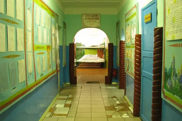 Вид из коридора на помещение с кроватями с надписью "спальное помещение отряда"